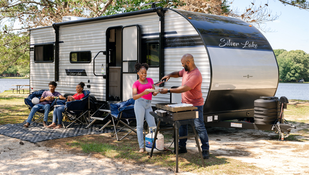 A family is having a picnic in front of a trailer
